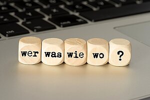 Würfel mit Aufschrift Wer, Was, Wie, Wo, ? auf Tastatur