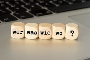 © iStock.com/Stadtratte Würfel mit Aufschrift Wer, Was, Wie, Wo, ? auf Tastatur
