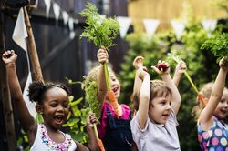Kinder freuen sich und halten Gemüse hoch