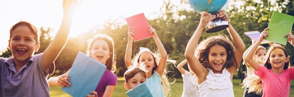rennende Kinder auf Wiese mit Schulmaterial