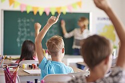 drei Schüler melden sich, im Hintergrund grüne Tafel